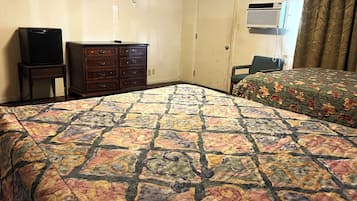 Una habitación de hotel con cama, cómoda, televisor y aire acondicionado.
