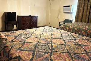 Una habitación de hotel con cama, cómoda, televisor y aire acondicionado.