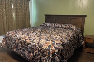 Una cama con una colcha estampada, un cabecero de madera y una mesita de noche.