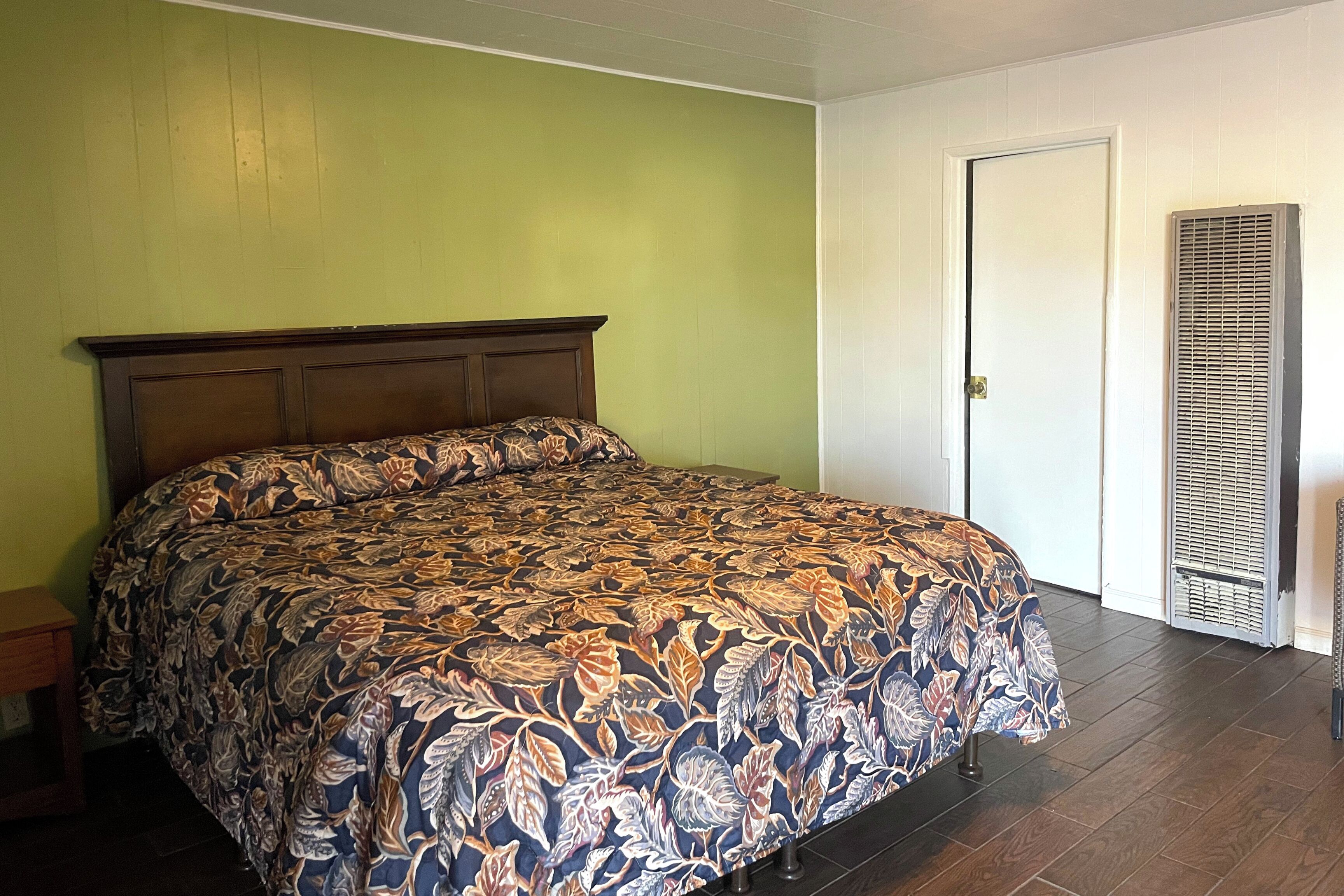 A bedroom with a bed, a door, and a wall-mounted air conditioning unit.