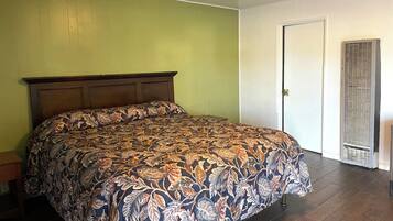 A bedroom with a bed, a door, and a wall-mounted air conditioning unit.