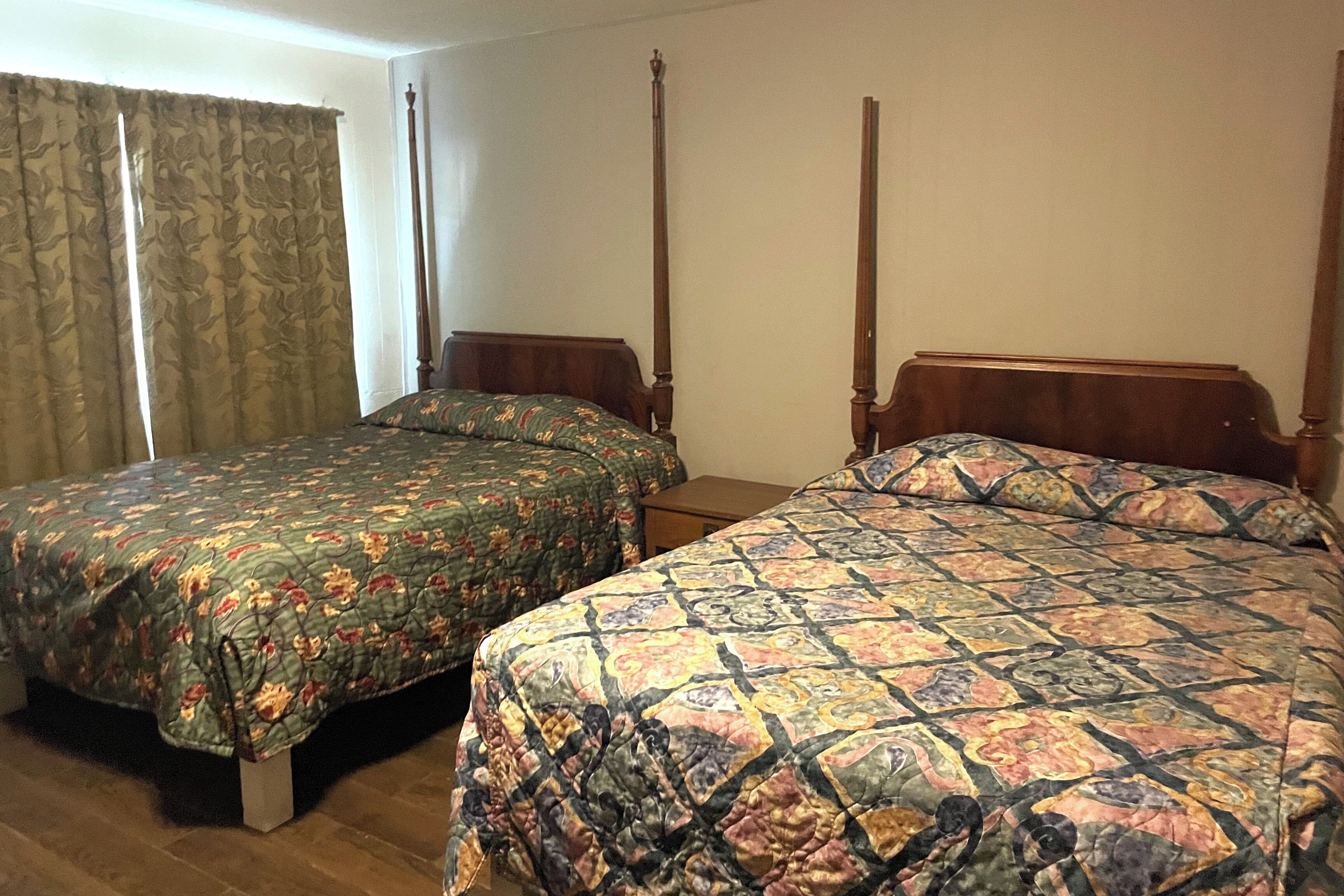 A room with two single beds, each with a wooden headboard and a floral-patterned bedspread.