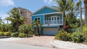 A two-story house with a blue exterior, a covered garage, and a paved driveway. - Beach Breezes: Pool & Spa, Ping Pong, 3 Blocks to Beach! (Holmes Beach)