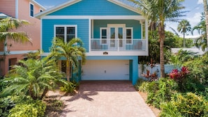 A two-story house with a blue exterior and a white garage door. - Beach Breezes: Pool & Spa, Ping Pong, 3 Blocks to Beach! (Holmes Beach)