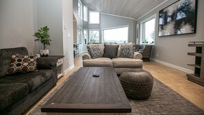A modern living room with a wooden coffee table, a beige sofa, and a dark-colored couch. - Sooke Waterfront Retreat – Hot Tub & Dock Access (Sooke)