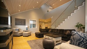 A modern living room with a staircase, a sofa set, a coffee table, and a rug. - Sooke Waterfront Retreat – Hot Tub & Dock Access (Sooke)