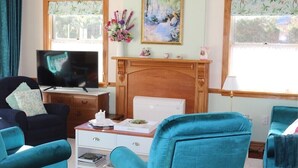 Ein Wohnzimmer mit Kamin, Fernseher und zwei Armstühlen in Türkis.