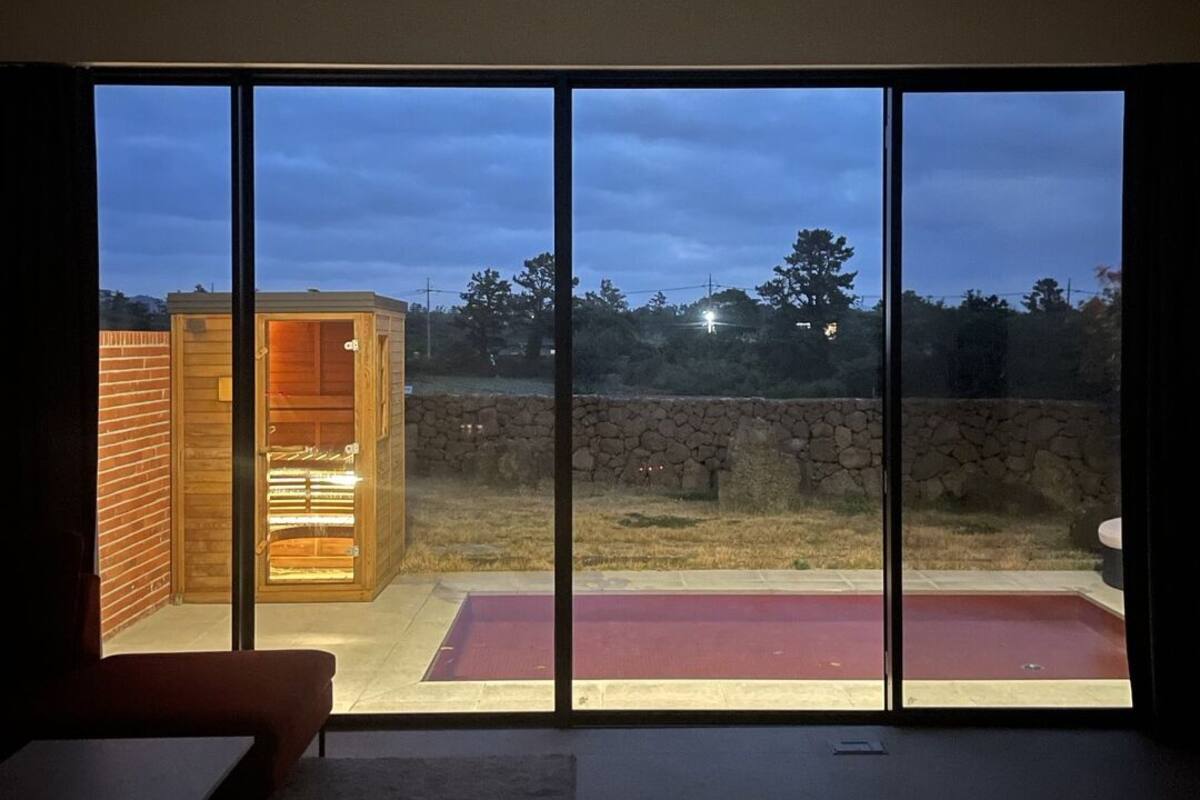 Une pièce dotée de grandes fenêtres, d’une structure en bois et d’un tapis rouge à l’extérieur.