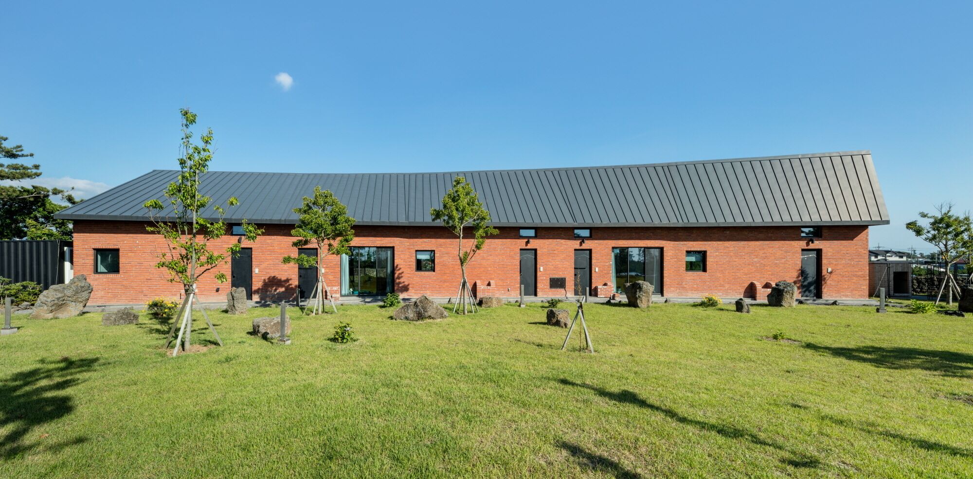A modern building with a brick facade, large windows, and a flat roof.