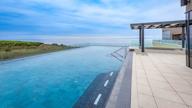 Ein Pool ohne Ende mit freiem Blick auf das Meer, einer Glasufernung und einer modernen Bauweise.