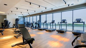 Ein Fitnessraum mit Trainingsgeräten, großen Fenstern und Holzboden.
