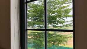 A window with a view of trees and a fence. - Milash Boutique Hotel (Bai Chay)
