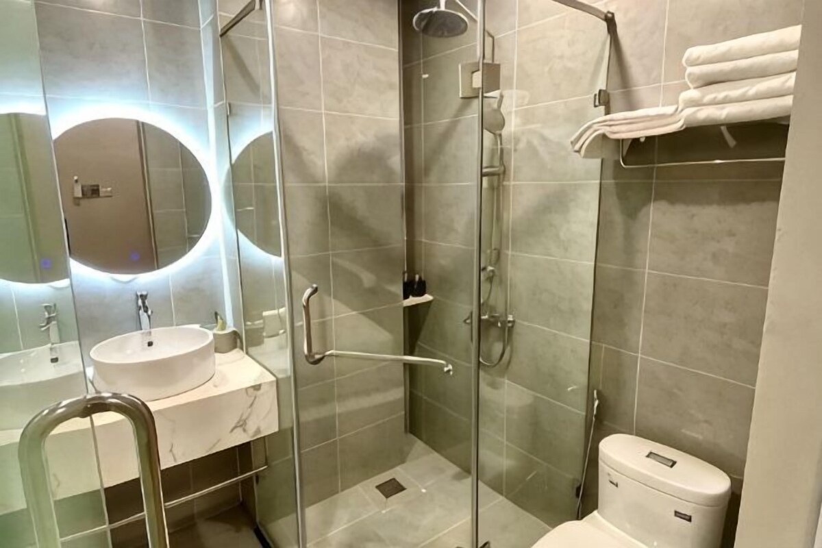 A modern bathroom with a glass-enclosed shower, a sink with a marble countertop, and a toilet.