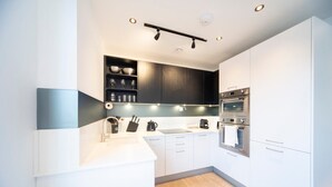 A modern kitchen with white cabinets, a black countertop, and stainless steel appliances. - Bright and Quiet | Spacious Apt with Balcony and Lift (Greater London)