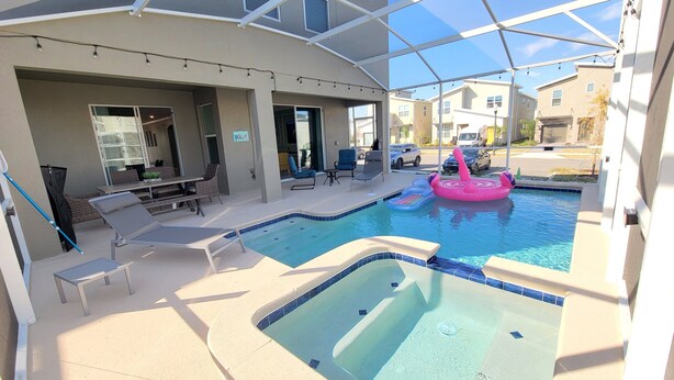 A pool area with lounge chairs, a hot tub, and inflatable toys.