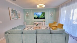 A living room with a sectional sofa, a television, and decorative wall panels.