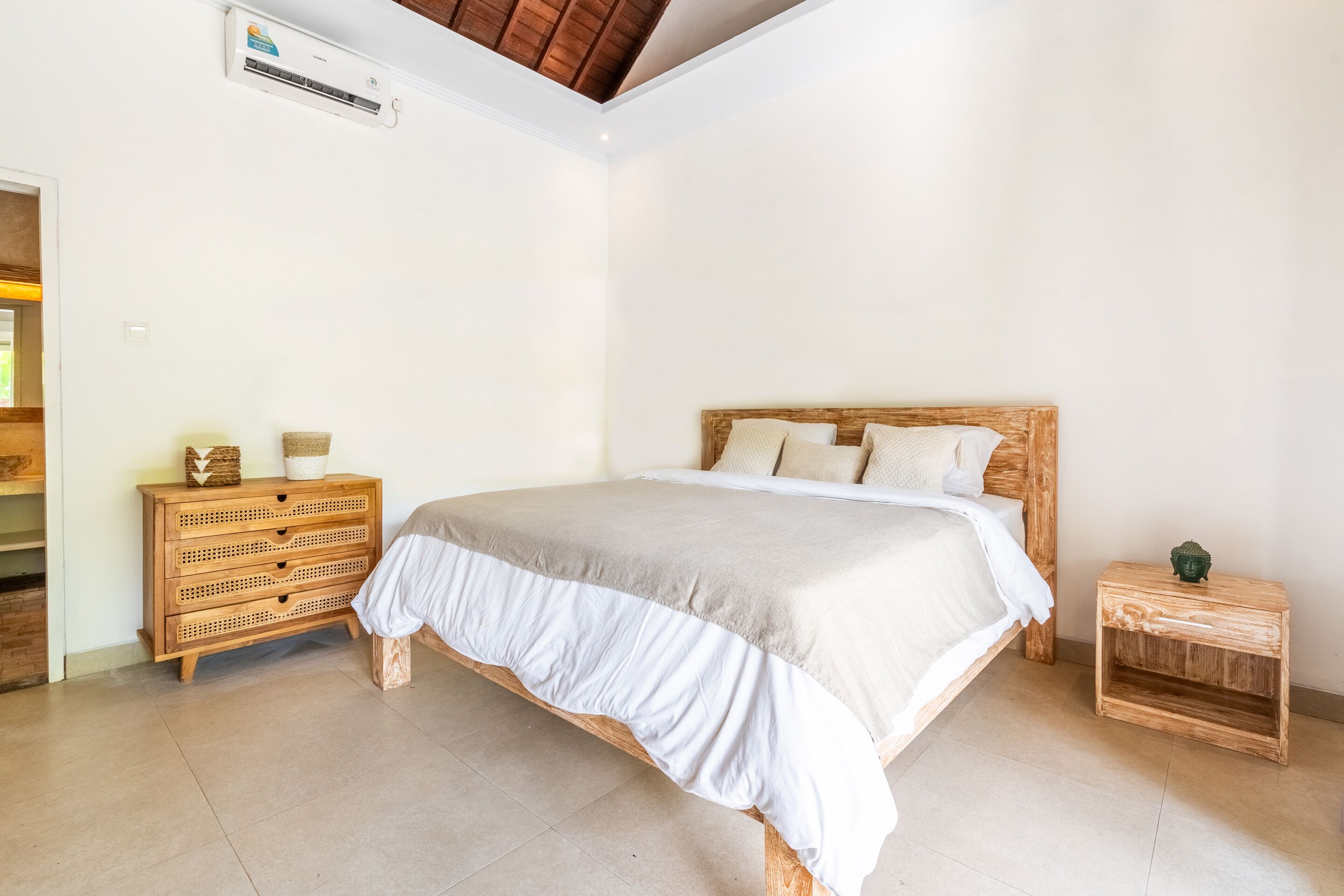 A bedroom with a wooden bed, a wooden nightstand, a wicker chest of drawers, and a ceiling fan.