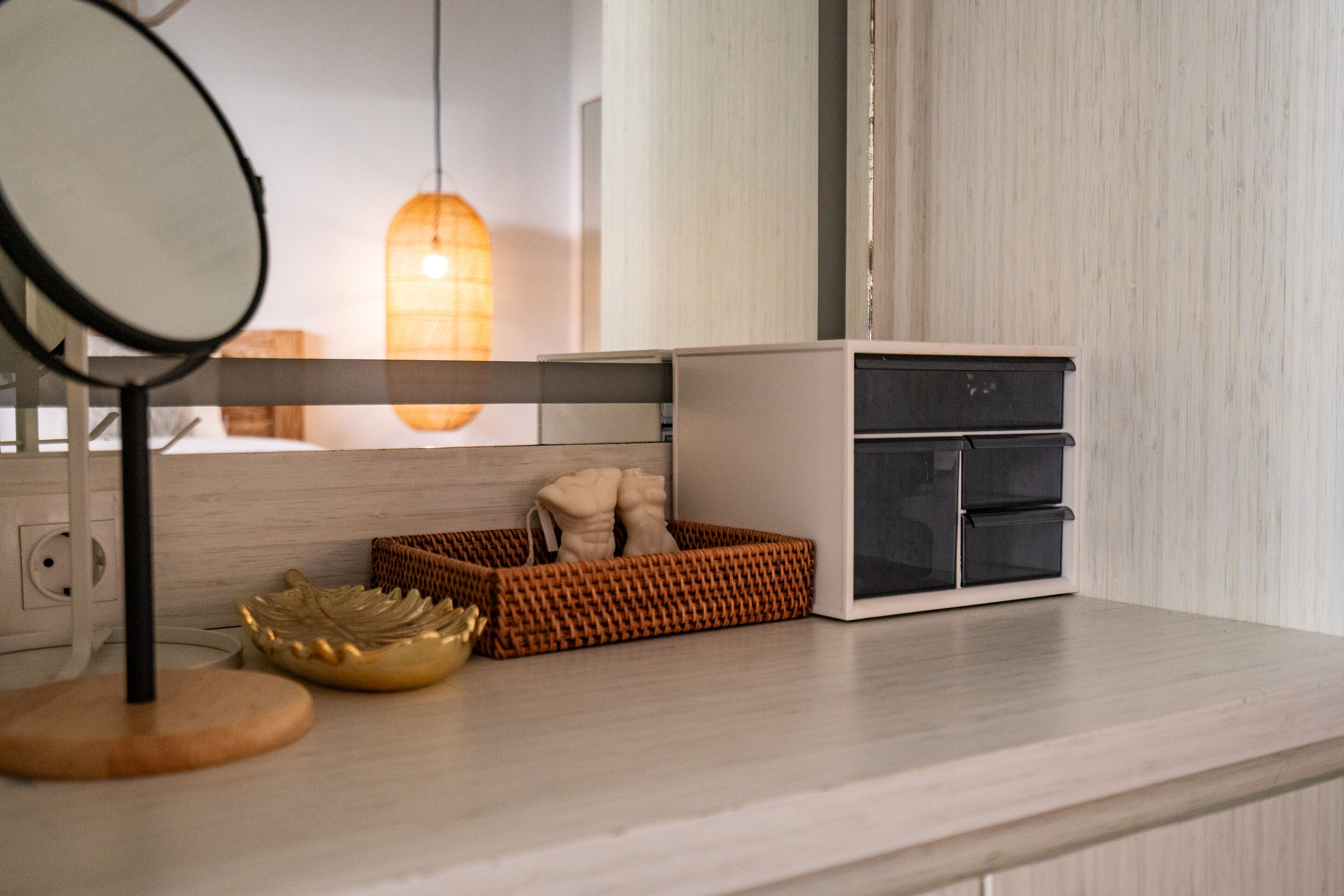 A modern kitchen with a wooden countertop, a white cabinet, a wicker basket, and a round mirror.