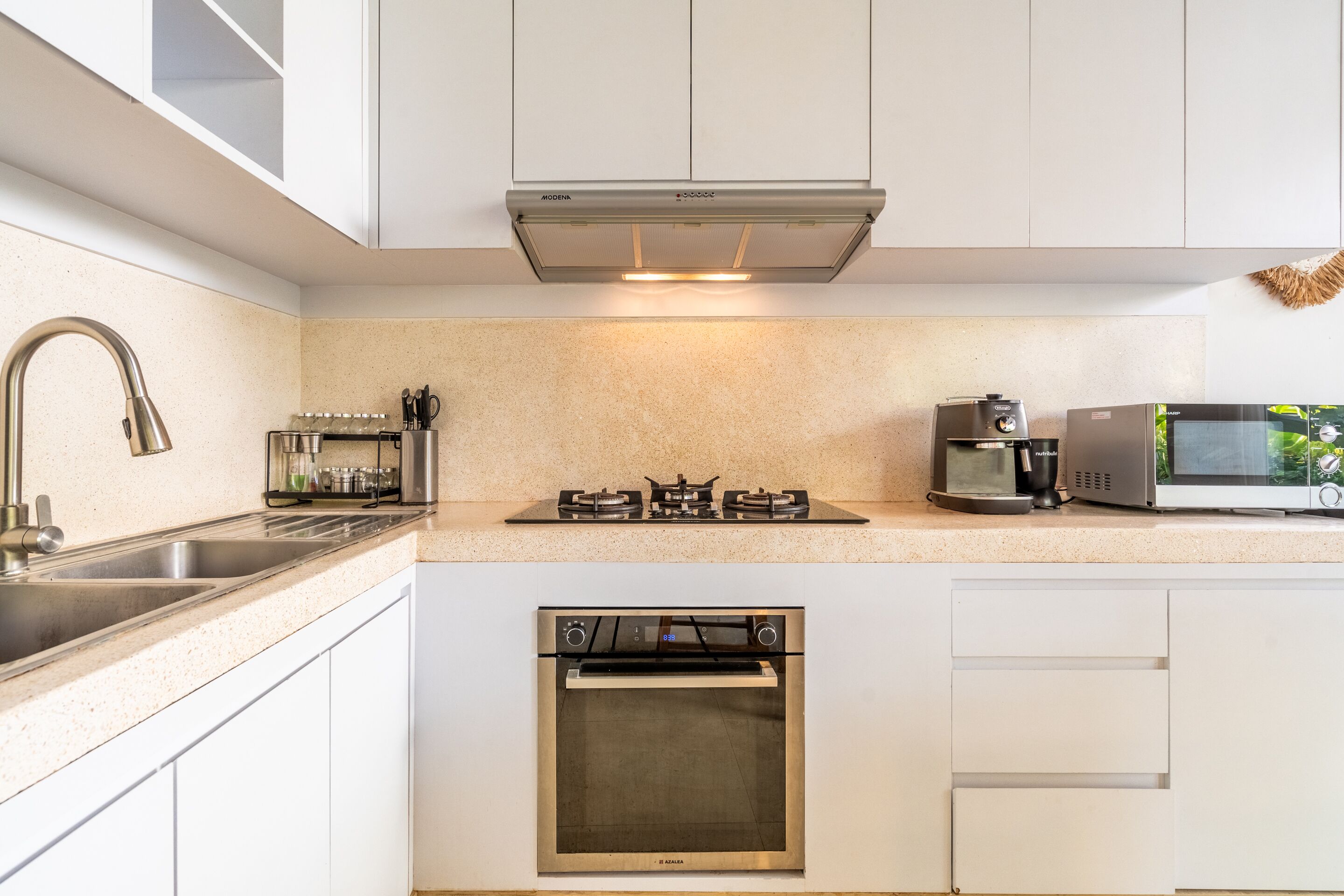 A modern kitchen with white cabinets, stainless steel appliances, a built-in oven, a microwave, and a gas stove.