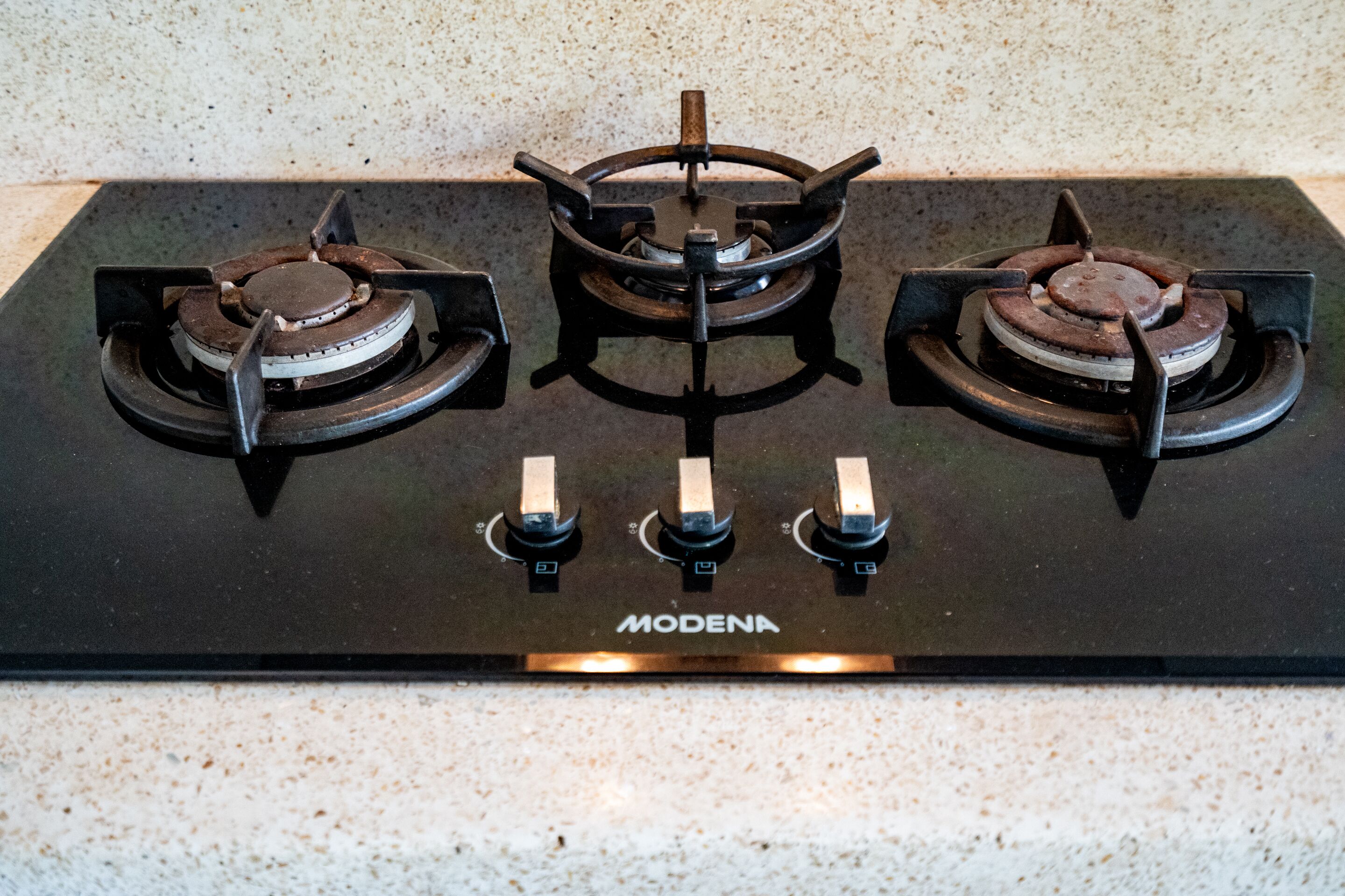 A black stovetop with three burners and a control panel labeled "MODENA."