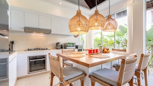 A modern kitchen with white cabinets, stainless steel appliances, and a central island with chairs. - Jungle Amaranth Villa Canggu - Exclusive 3BR Retreat with Pool, Modern Amenities and Top Location (Canggu)
