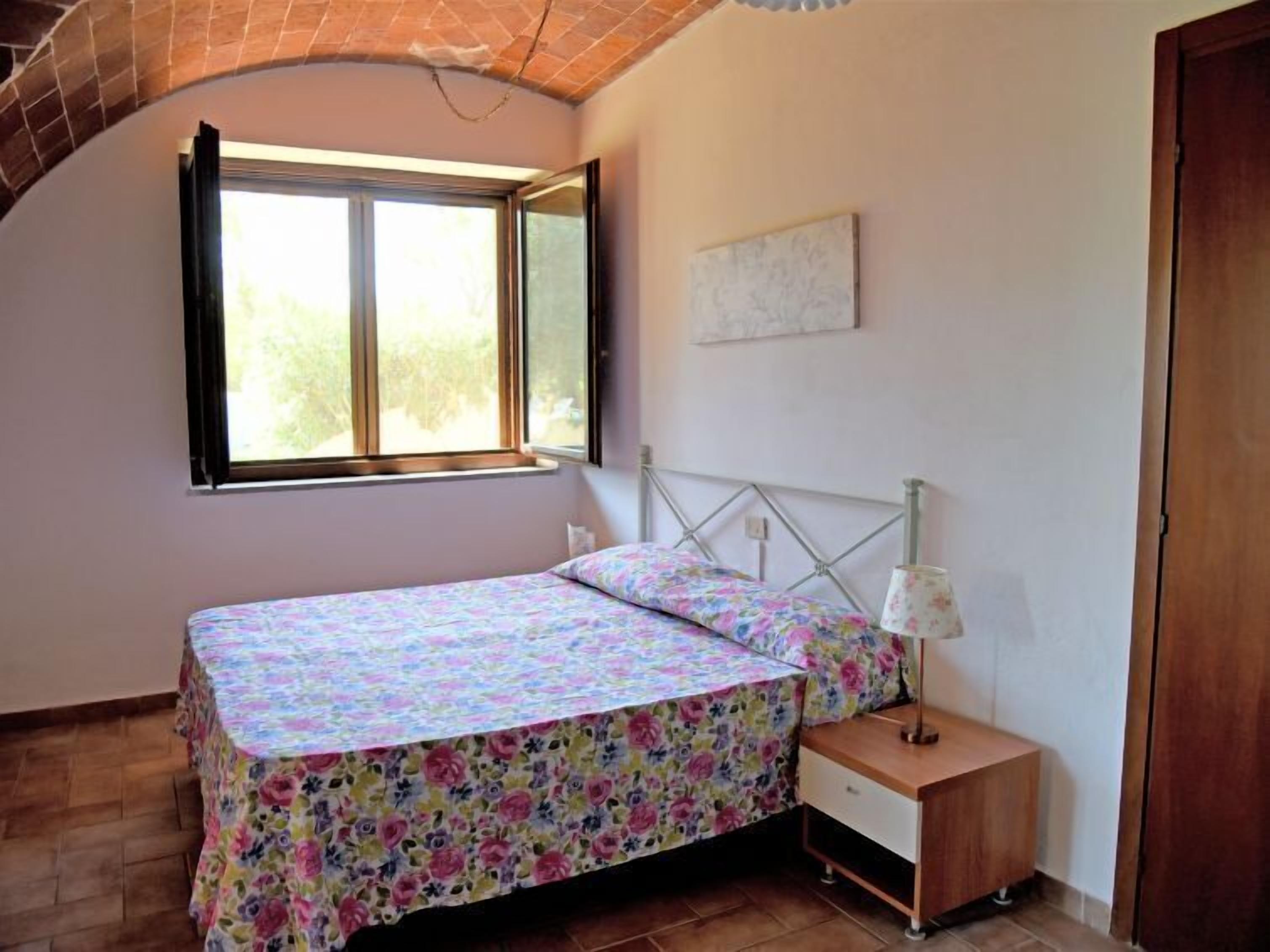 Une chambre à coucher avec un lit, une table de chevet, une fenêtre et une porte.