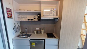 A compact kitchenette with a microwave, sink, and storage cabinets. - Loft moderno con vista a los cerros  (Bogotá)
