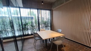 A modern meeting room with a large table, four chairs, and large windows offering a view of the street. - Loft moderno con vista a los cerros  (Bogotá)