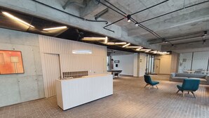 A spacious lobby with a reception desk, seating area, and exposed ductwork on the ceiling. - Loft moderno con vista a los cerros  (Bogotá)