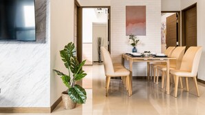 A modern dining area with a marble wall, a flat-screen TV, a potted plant, and a wooden dining table with chairs. - High Floor New Bldg 5★ Ximending, Stunning Views (Taipei City)