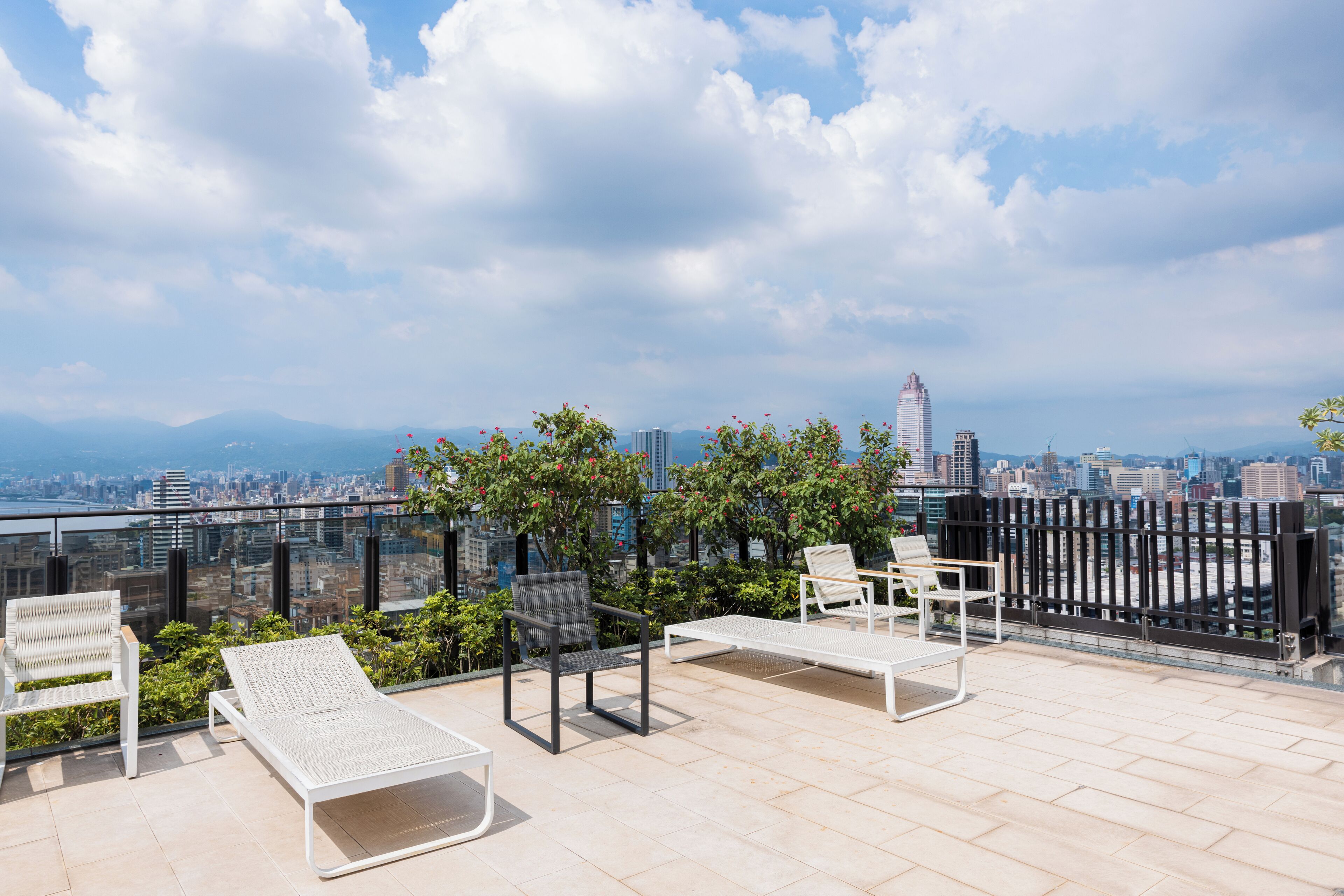 A rooftop terrace with lounge chairs and a table, offering a city view.