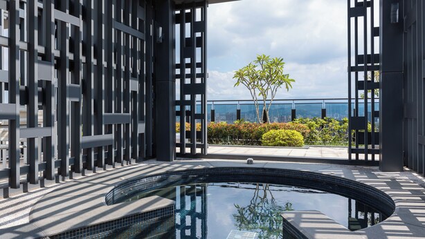 A modern indoor pool area with a curved design, surrounded by a geometric metal fence, and a view of a landscaped garden and city skyline. - High Floor New Bldg 5★ Ximending, Stunning Views (Taipei City)