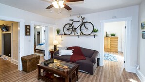 Un salon avec un canapé, une table basse et un vélo accroché au mur.