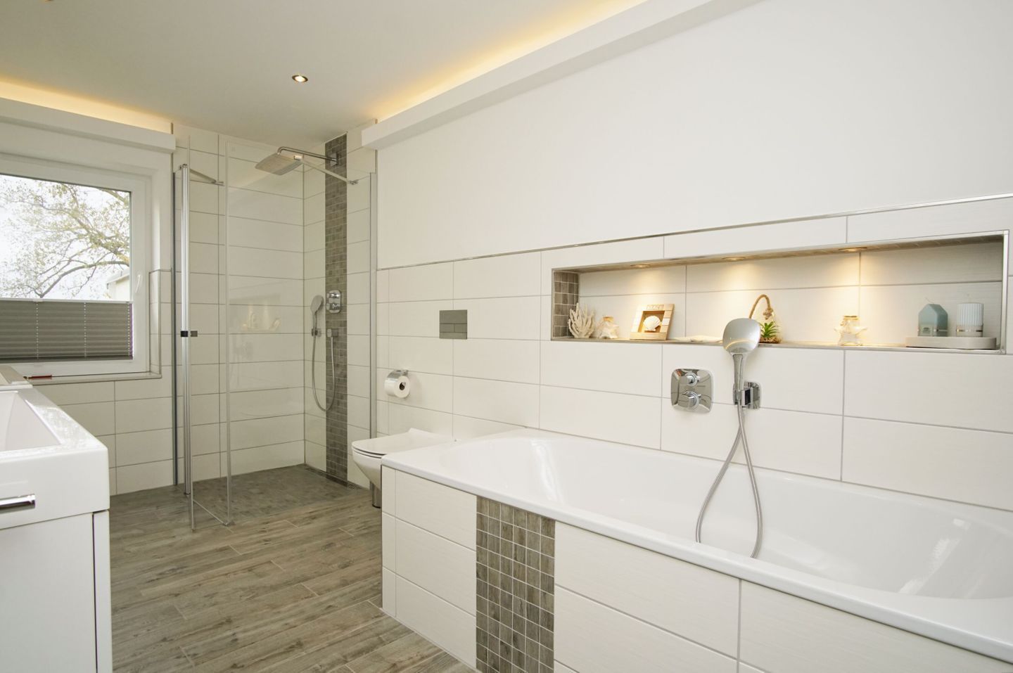 Un baño moderno con ducha, inodoro y bañera, que cuenta con piso de cerámica y una ventana.