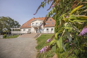 Une maison à deux étages avec un balcon, une entrée principale et une allée pavée.
