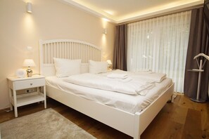 Un lit bien fait, avec du linge de lit blanc, une table de chevet avec une lampe et une fenêtre avec des rideaux.