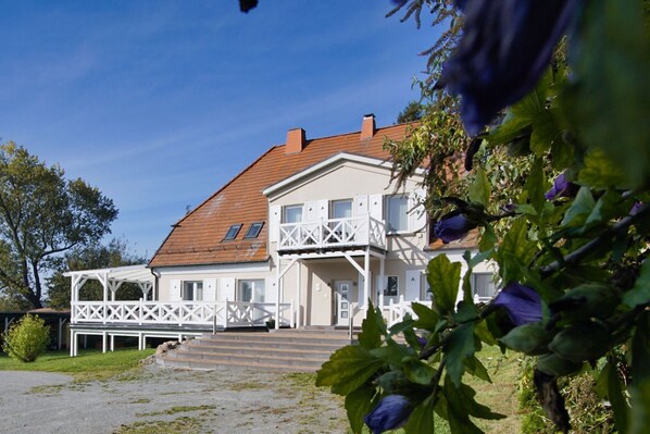 A two-story house with a balcony, a covered porch, and a front entrance. - Ruhig und Idyllische Lage, Ahoi Erlebnisbad Gratis - Gutshaus Silvitz Fewo 01 - Gutshaus Silvitz (Bergen auf Rügen)