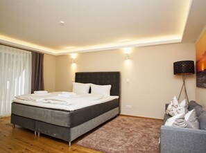 A bedroom with a bed, bedside lamps, a sofa, and a carpeted floor. - Ruhig und Idyllische Lage, Ahoi Erlebnisbad Gratis - Gutshaus Silvitz Fewo 01 - Gutshaus Silvitz (Bergen auf Rügen)