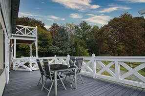 A wooden deck with a white railing, a covered seating area, and a view of trees. - Ruhig und Idyllische Lage, Ahoi Erlebnisbad Gratis - Gutshaus Silvitz Fewo 01 - Gutshaus Silvitz (Bergen auf Rügen)