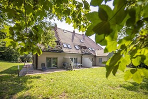 A house with a sloped roof, large windows, and a covered patio area. - Ruhig und Idyllische Lage, Ahoi Erlebnisbad Gratis - Gutshaus Silvitz Fewo 02 - Gutshaus Silvitz (Bergen auf Rügen)