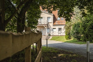 A building with a front porch, a staircase leading to the entrance, and a gravel driveway.