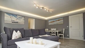 Una sala de estar moderna con un sofá gris, una mesa de centro blanca y dos cuadros en la pared.