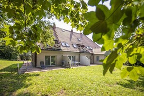 A house with a sloped roof, large windows, and a covered patio area. - Ruhig und Idyllische Lage, Ahoi Erlebnisbad Gratis - Gutshaus Silvitz Fewo 02 - Gutshaus Silvitz (Bergen auf Rügen)