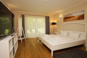 A hotel room with a large bed, a desk with a computer, a TV, and a painting on the wall. - Ruhig und Idyllische Lage, Ahoi Erlebnisbad Gratis - Gutshaus Silvitz Fewo 02 - Gutshaus Silvitz (Bergen auf Rügen)