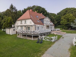 A two-story house with a balcony, a covered porch, and a gravel driveway. - Ruhig und Idyllische Lage, Ahoi Erlebnisbad Gratis - Gutshaus Silvitz Fewo 02 - Gutshaus Silvitz (Bergen auf Rügen)