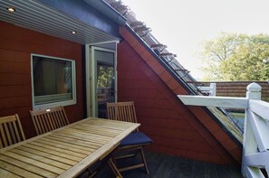 A wooden table and chairs outside a building with a red wall and a white railing. - Ruhig und Idyllische Lage, Ahoi Erlebnisbad Gratis - Gutshaus Silvitz Fewo 03 - Gutshaus Silvitz (Bergen auf Rügen)