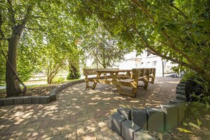 A paved outdoor area with a wooden bench and a brick border. - Ruhig und Idyllische Lage, Ahoi Erlebnisbad Gratis - Gutshaus Silvitz Fewo 03 - Gutshaus Silvitz (Bergen auf Rügen)