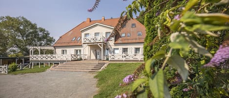 Ein zweistöckiges Haus mit Balkon, Eingang und gepflasterter Auffahrt.