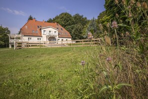 A large house with a red roof, a balcony, and a grassy lawn. - Ruhig und Idyllische Lage, Ahoi Erlebnisbad Gratis - Gutshaus Silvitz Fewo 03 - Gutshaus Silvitz (Bergen auf Rügen)