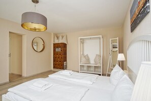 Een hotelkamer met een groot bed, een kledingkast, een spiegel en een hanglamp.